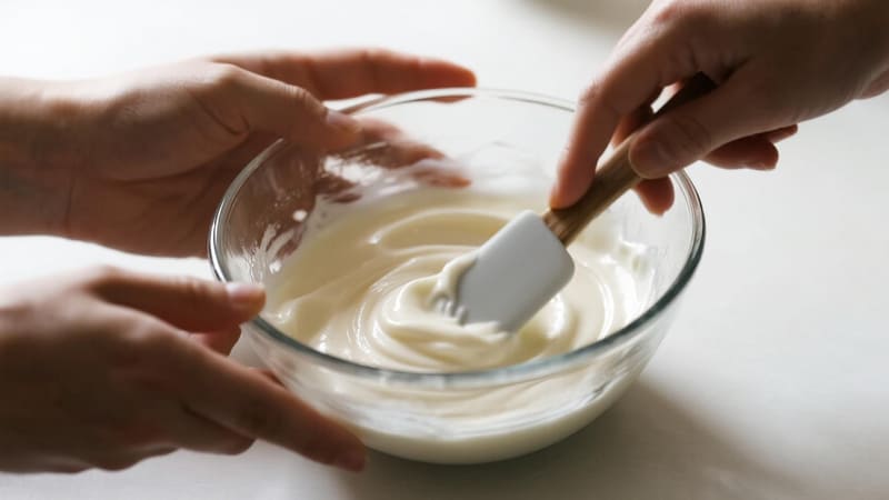 A person mixing cream in a bowl with a spatula