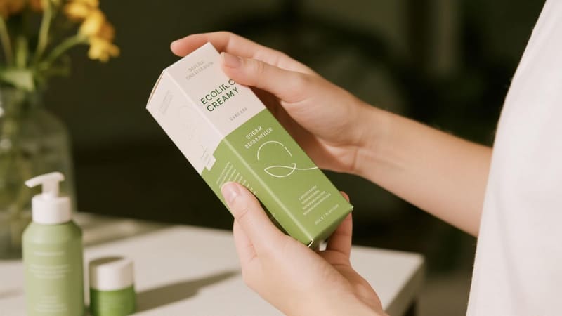 A consumer carefully reading the eco-friendly details on a cream box